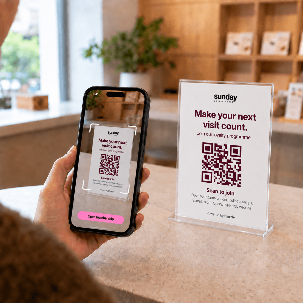 A customer scans the updated Sunday Coffee join sign on a café counter. Illustrative membership journey.